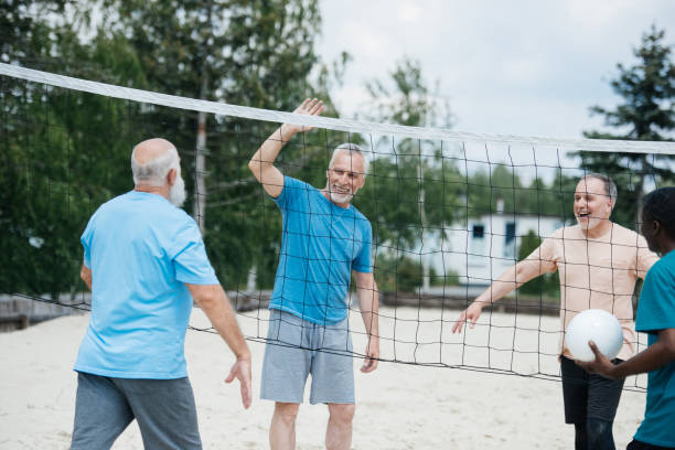 istock multicultural old friends playing volleyball on beach on summer day 1012513584