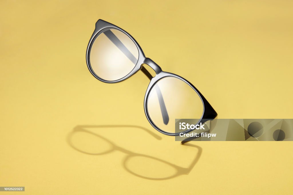 Flying black glasses Studio shot of flying black glasses with shadow on yellow background. Eyeglasses Stock Photo