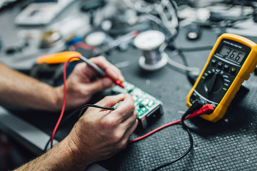 Electrician repairing fuse box with screwdriver, closeup