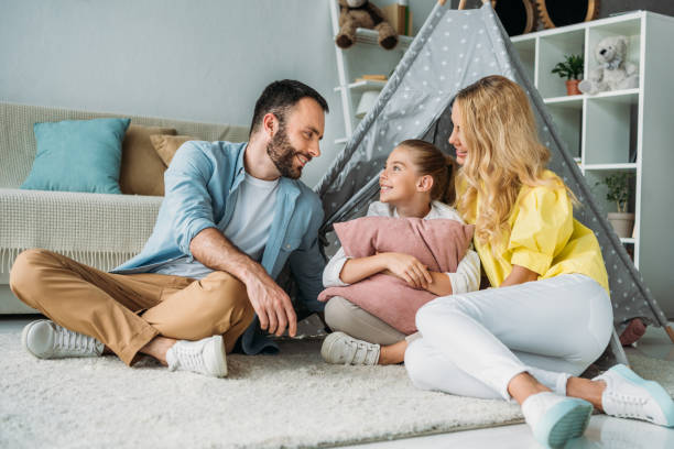 istock happy young family sitting on floor with teepee 1012530642