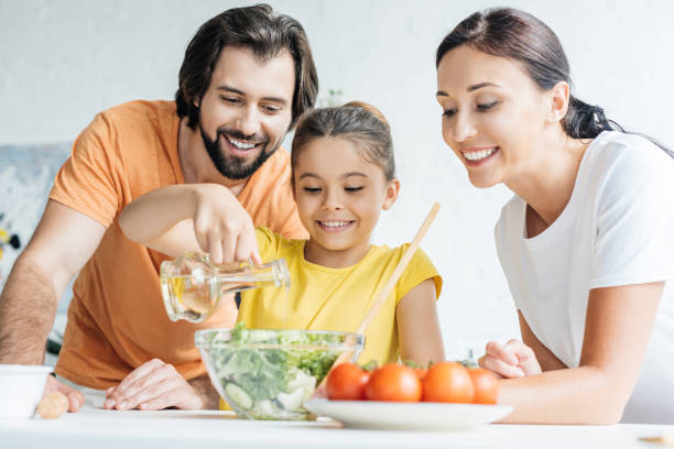 istock beautiful young family preparing salad together at kitchen 1012531674