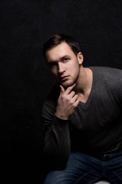 istock Handsome tough guy on a black background. Hand at the face. 1012531724