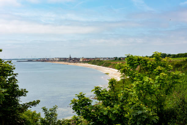 Panoramic vista of Bridlington and Bridlington Bay from the cliff tops at Sewerby, England. Bridlington is a Yorkshire coast seaside resort on the North Sea that is very popular with tourists and holiday-makers.  It has a busy, thriving fishing industry that is well known for its shellfish.  The town harbour hosts moorings for pleasure craft such as yachts and motor launches, speedboats and even a pirate ship that takes children and parents on trips along the east coast.  The population of the town is around 35,000 and it is situated about 24 miles north of the city of Hull.  Sewerby lies just north of Bridlington along the east coast of England. east riding of yorkshire photos stock pictures, royalty-free photos & images