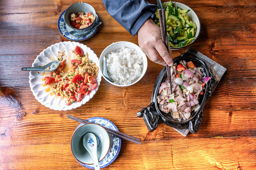 overhead view on wooden table with man eating chinese food