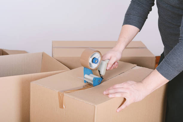 istock Man sealing a shipping cardboard box 1012543450