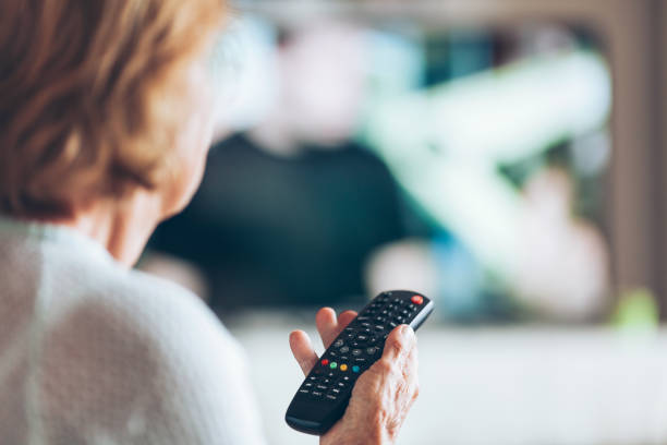 istock Senior woman with remote control watching tv 1012561288