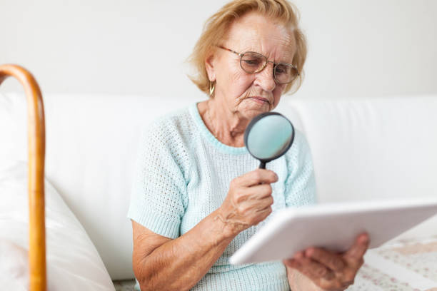 istock Elderly woman with glasses and loupe using a digital tablet 1012562452