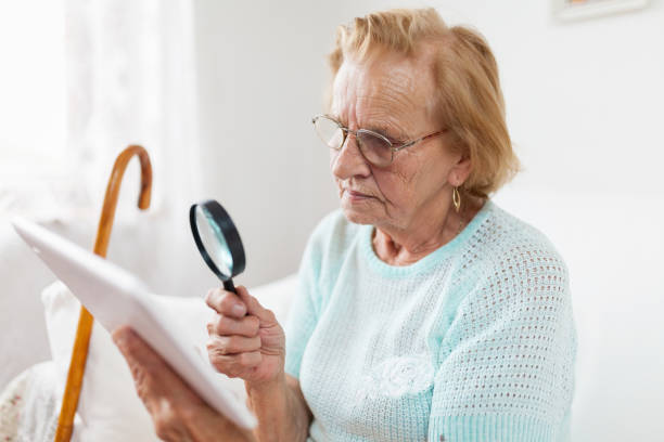 istock Elderly woman with glasses and loupe using a digital tablet 1012562508