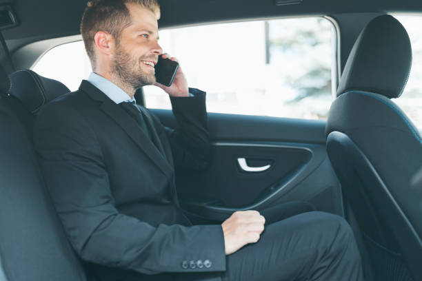 istock Executive businessman at the back of car using a mobile phone 1012562750