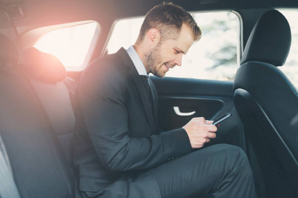 istock Executive businessman at the back of car using a mobile phone 1012562824