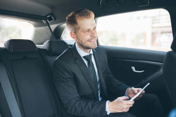 istock Executive businessman at the back of car using a digital tablet 1012566676
