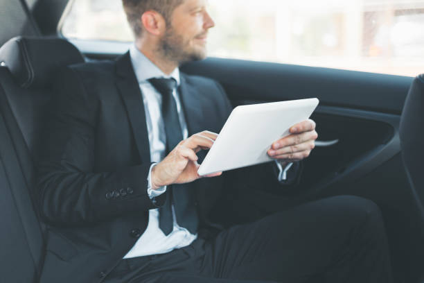 istock Executive businessman at the back of car using a digital tablet 1012567090