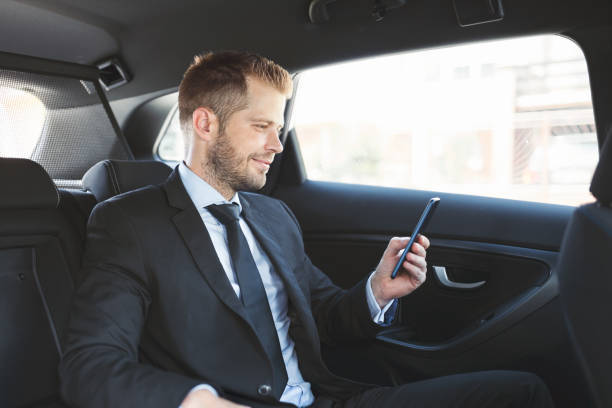 istock Executive businessman at the back of car using a mobile phone 1012569246