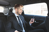 Executive businessman at the back of car using a mobile phone
