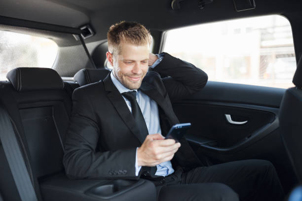 istock Executive businessman at the back of car using a mobile phone 1012569314