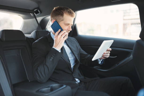 istock Executive businessman at the back of car using a mobile phone 1012569436