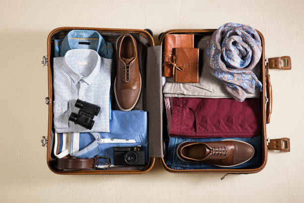 istock Open packed suitcase with vacation accessories isolated on beige background 1012574674