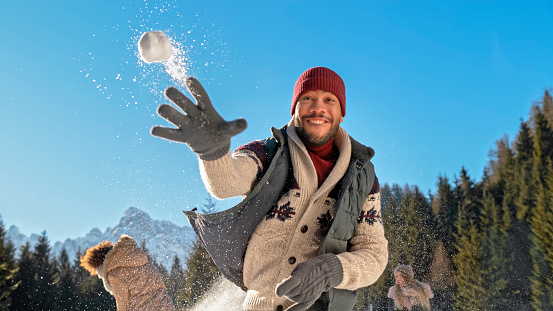 Portrait of man throwing snowball in air.