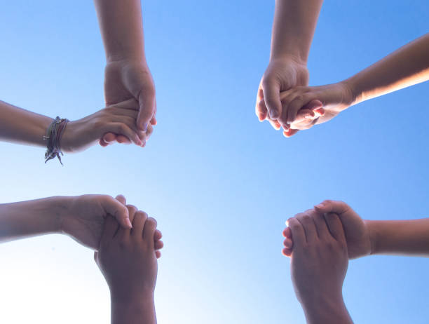 istock Group of People Praying in a Circle Holding Hands 1012589862
