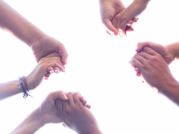 istock Group of People Praying in a Circle Holding Hands 1012589900