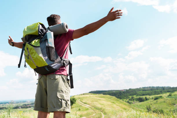 istock tourist with backpack standing with outstretched hands on summer meadow with cloudy sky 1012593340