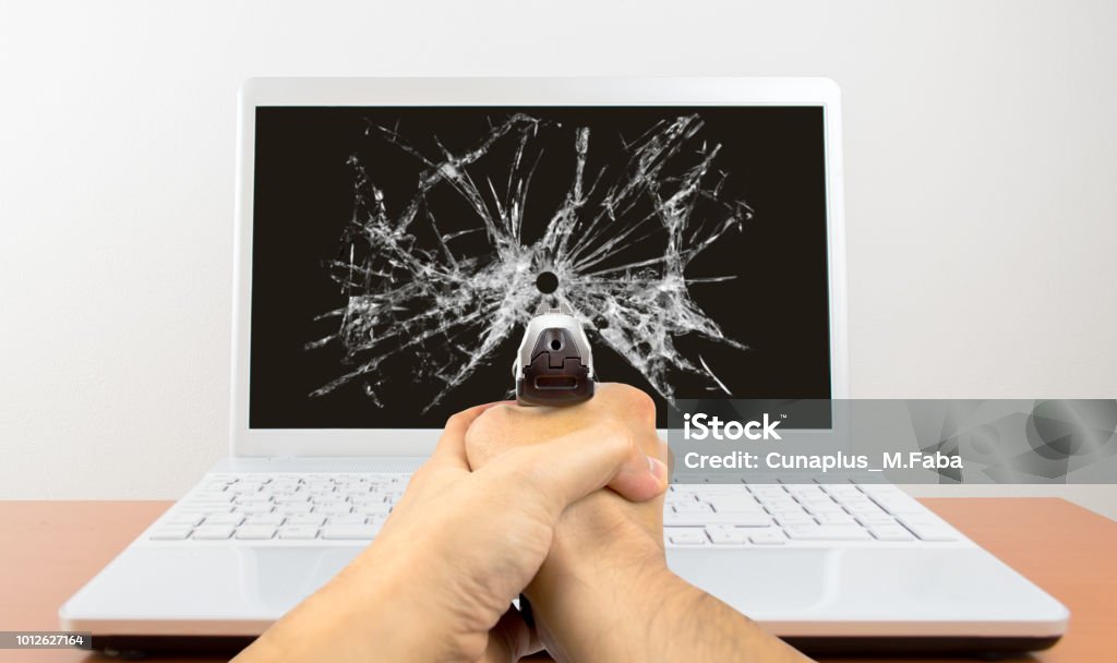 stressful job Man shoots with gun at his laptop Shooting a Weapon Stock Photo