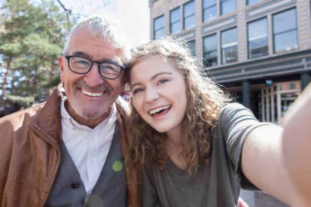 teenager-mädchen nimmt selfie mit großvater - teenager alter stock-fotos und bilder