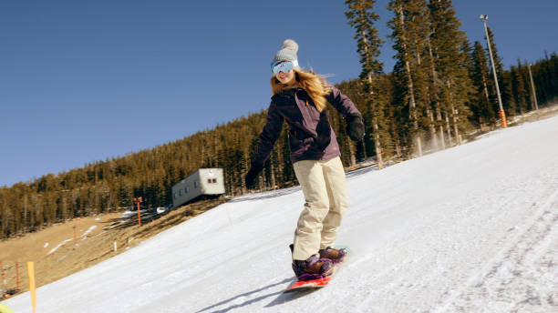 snowboarder femenina se concentra como desciende la pista de esquí - clear sky diagonal snow winter fotografías e imágenes de stock