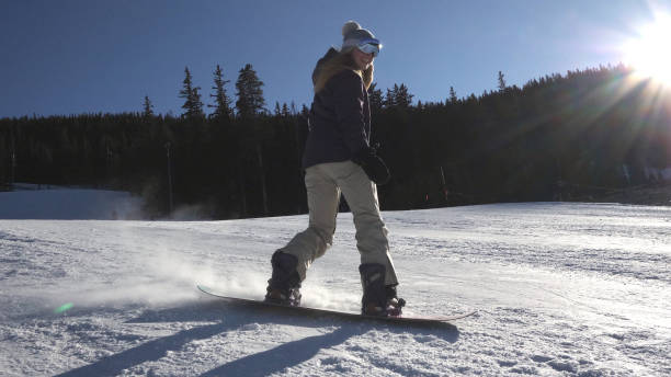 istock Young woman rides down a ski slope on her snowboard 1012627364
