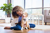 istock Young woman plays with new puppy at home 1012627576