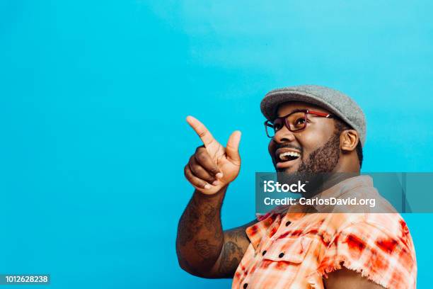 Portrait Of A Laughing Man In Orange Shirt Pointing With Finger And Looking Up Stock Photo - Download Image Now