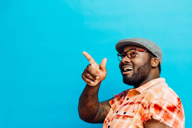 portrait of a laughing man in orange shirt pointing with finger and looking up - portrait human face men overweight imagens e fotografias de stock