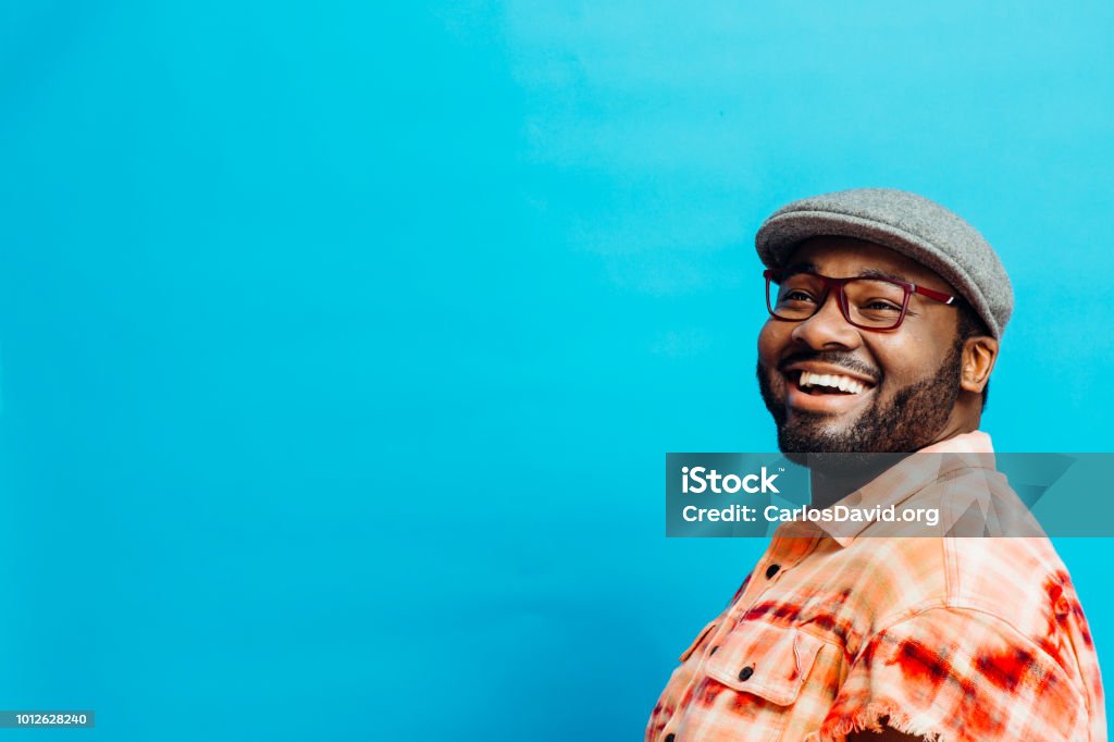 Portrait of a happy man in orange shirt looking up Portrait of a happy man in orange shirt looking up, with blue copy space around him People Stock Photo