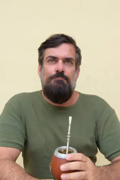 Middle-aged bearded man holding a container of yerba mate traditionally used in southern Brazil and also in Argentina, Uruguay and Paraguay