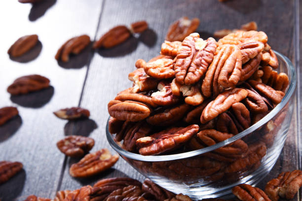 istock Bowl with pecan nuts on wooden table. 1012688278