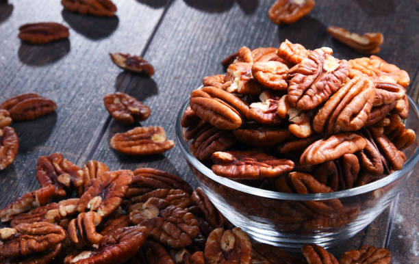 istock Bowl with pecan nuts on wooden table. 1012688298