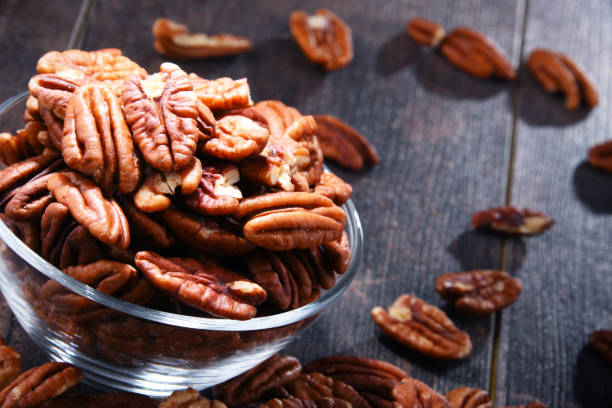 istock Bowl with pecan nuts on wooden table. 1012688334