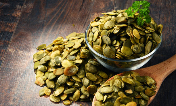 istock Composition with bowl of pumpkin seeds on wooden table 1012690614