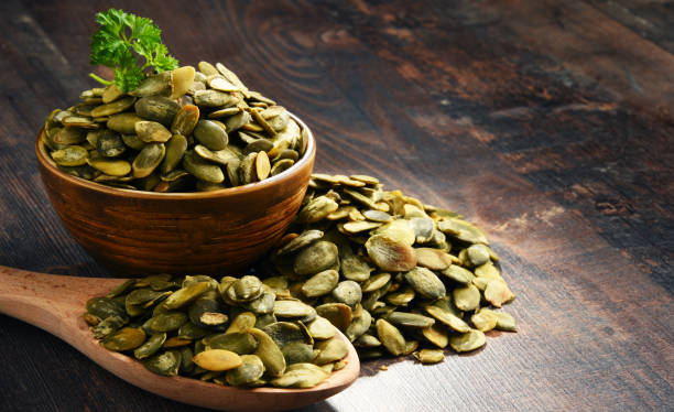 istock Composition with bowl of pumpkin seeds on wooden table 1012690638