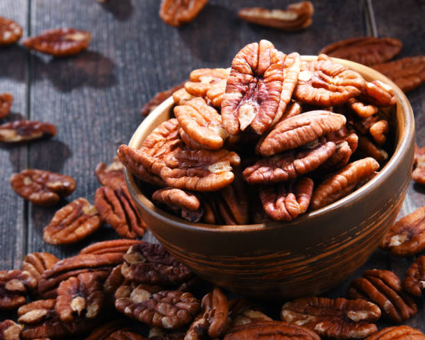 istock Bowl with pecan nuts on wooden table. 1012702352