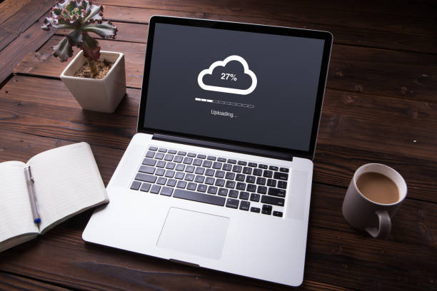 Cloud upload processing data on laptop with internet with office equipment and wooden desk background stock photo