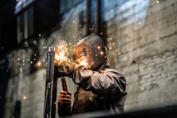 industrial worker welding steel - soldar imagens e fotografias de stock