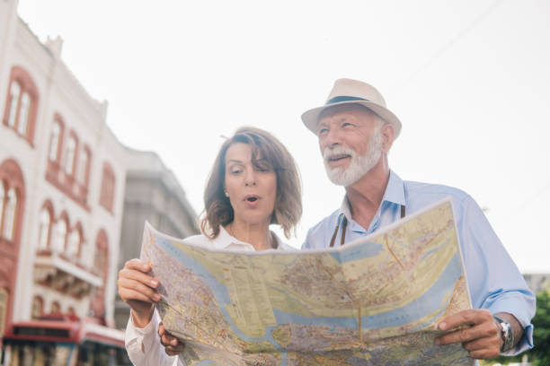 istock Older woman talking to a man and looking touristic map 1012749626
