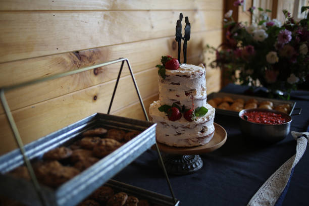 istock Delicious wedding reception dessert table with Wedding cake, chocolate chip cookies, and strawberry shortcake - Rustic wedding with wooden background and wildflowers 1012754072