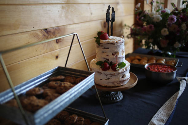 istock Delicious wedding reception dessert table with Wedding cake, chocolate chip cookies, and strawberry shortcake - Rustic wedding with wooden background and wildflowers 1012754074