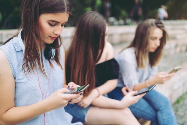 istock Three teenage girls using phones individually 1012754626
