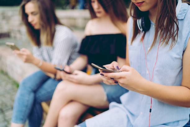 istock Three teenage girls using phones individually 1012754702