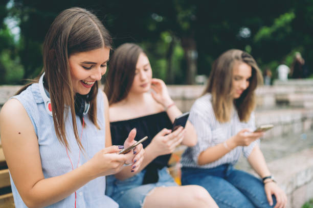 istock Three teenage girls using phones individually 1012757818