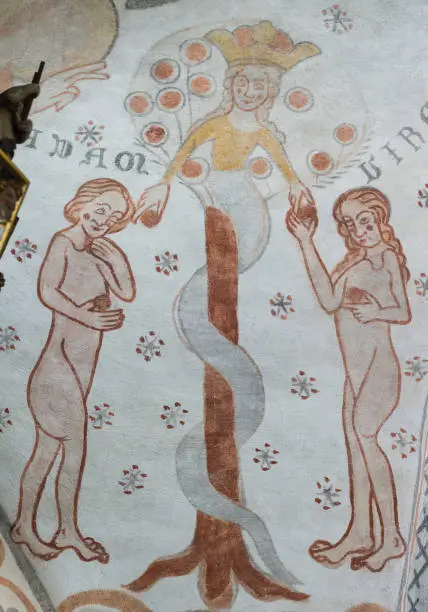 The fall of man in the garden of paradise. The serpent gives the forbidden fruit to Adam and Eve. Kirkerup church , Denmark, July 3, 2018