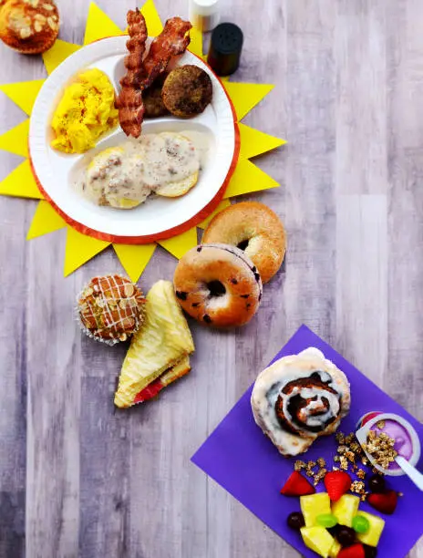 Various breakfast foods arranged on a bright paper/wood grain background.